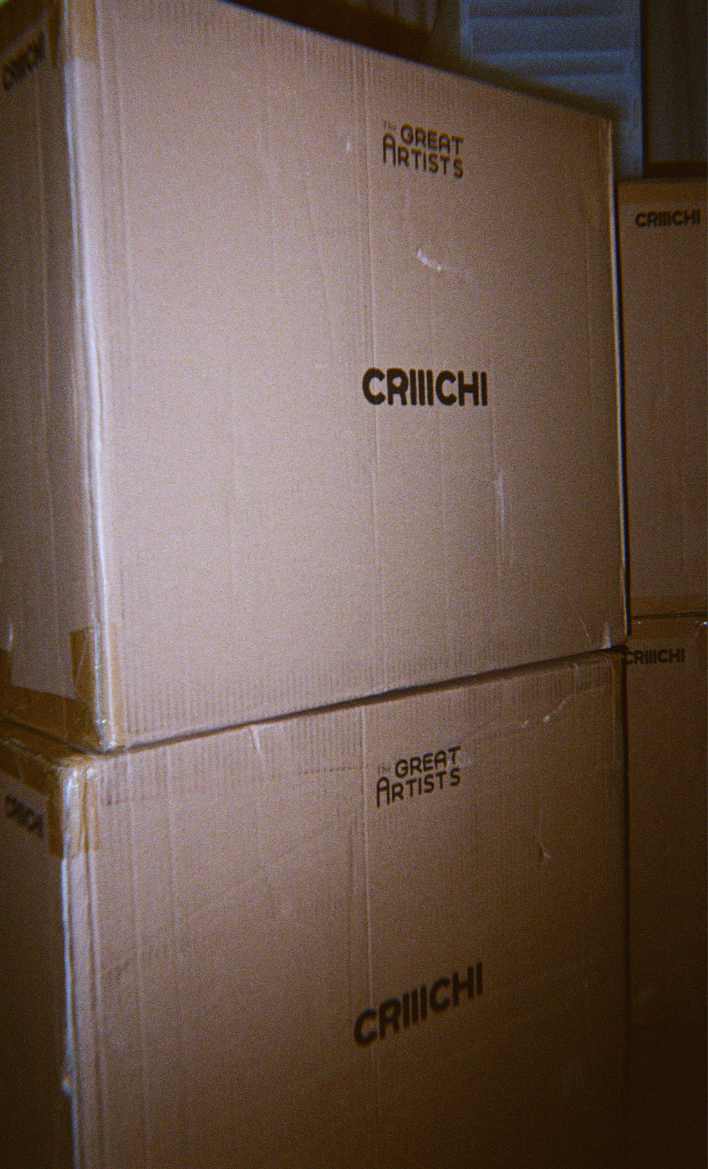 Stack of cardboard boxes with 'CRIIICHI' and 'The Great Artists' branding.
