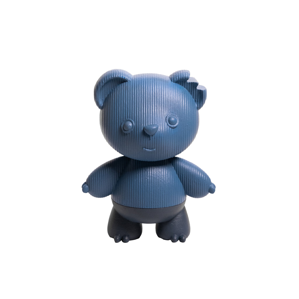 A small stylized bear figurine or toy in a textured blue color with darker gray feet, standing against a plain white background.