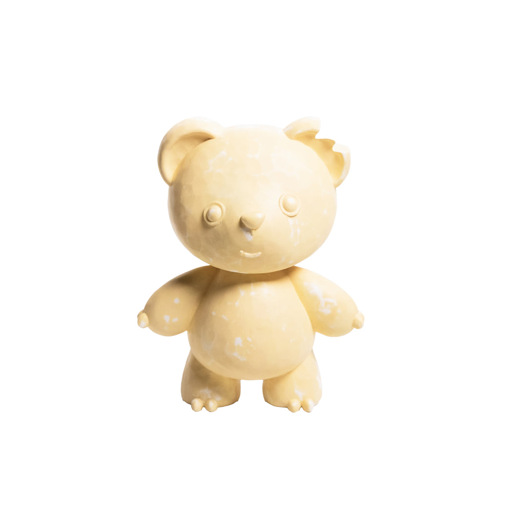 A small beige teddy bear figurine with a distressed, weathered texture, standing against a solid white background.