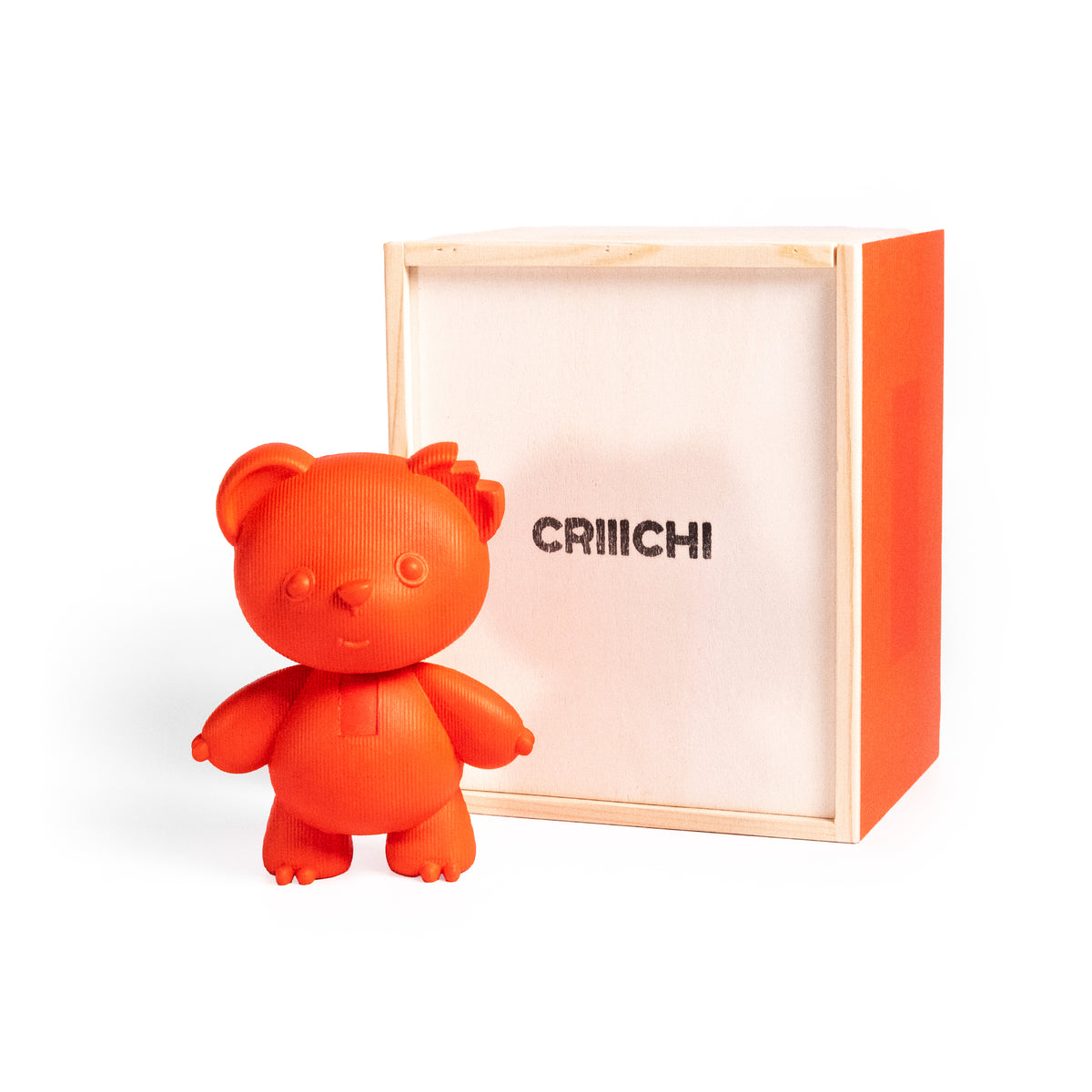 An orange bear-shaped figurine standing in front of its light wood and orange box, with the brand name 'CRIIICHI' printed on the box.