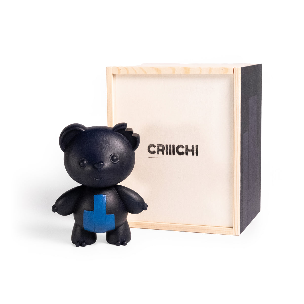 A black bear figurine with a blue paint stroke on its chest stands in front of a light wood box with the brand name 'CRIIICHI' printed on the inside.